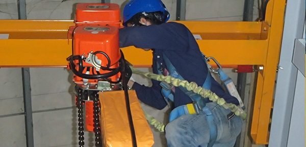 A technician inspecting the hoist mechanism of an overhead travelling crane